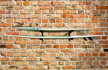 Load image into Gallery viewer, Wall mounted surfboard racks mounted to brick wall powder coated black to hold 2 surfboards or mal